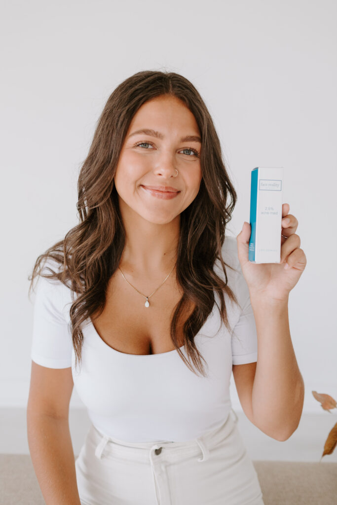 Esthetician holding product up to face smiling